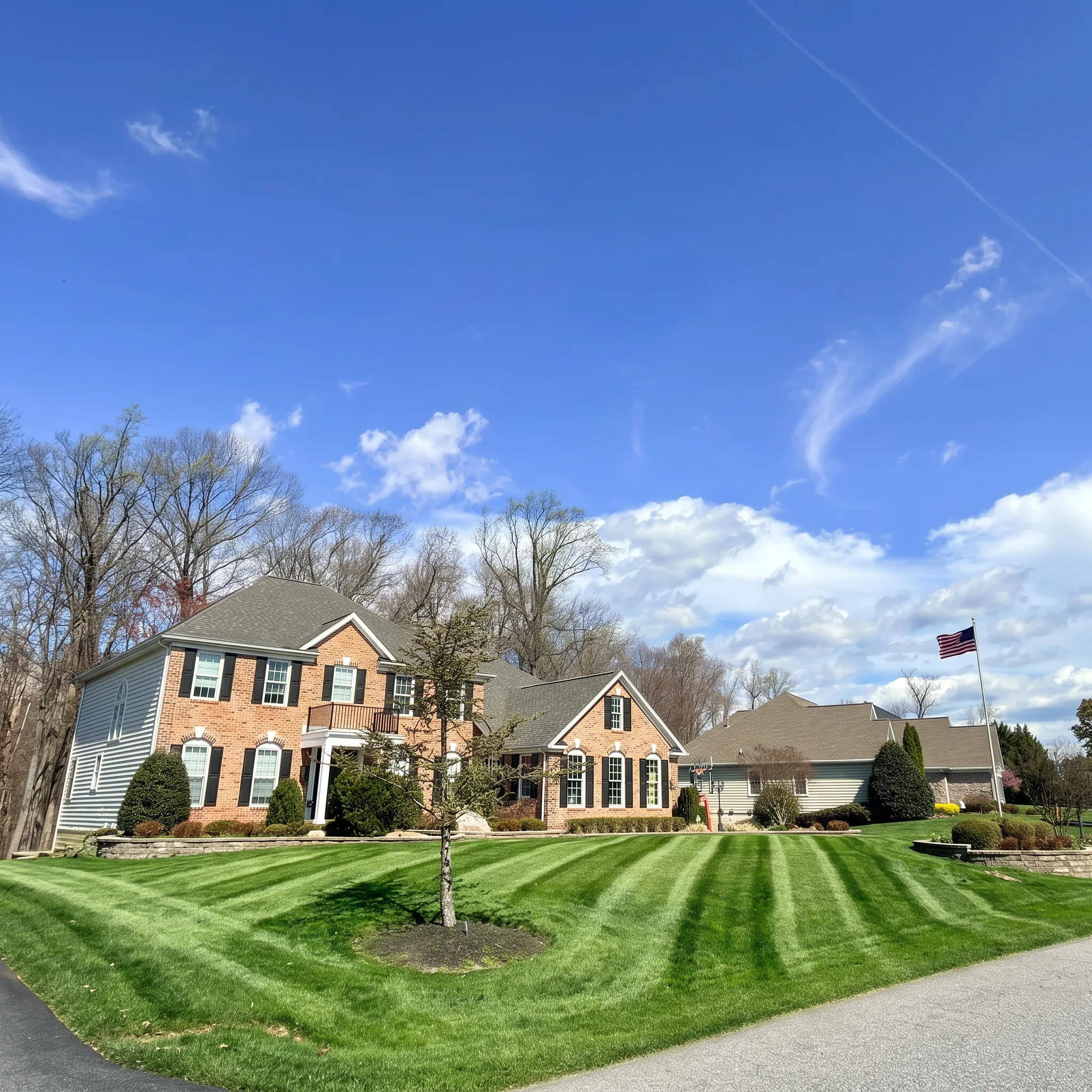 Freshly mowed striped lawn in front of a brick colonial home in Harford County, MD